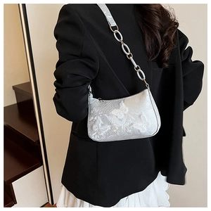 Detail of silver crossbody bag featuring 3D butterfly embroidery and chain strap