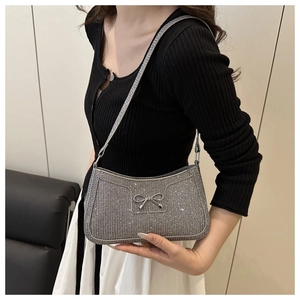 Dettaglio di una borsa a spalla in paillettes argento con elegante fiocco decorativo