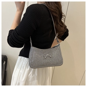 Detail of silver glitter baguette bag with metallic bow showing on shoulder fit