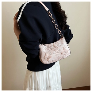 Detail of pink embroidered tote bag featuring 3D butterfly appliques and resin chain strap
