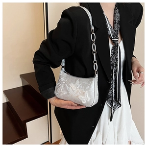 Detailed view of silver shoulder bag with 3D butterfly pattern and acrylic chain strap