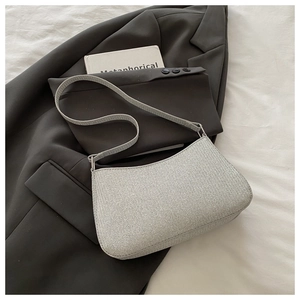 Détail d'un sac à main gris clair texturé posé sur une veste de tailleur grise