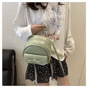 Detail showing mint green mini backpack with a leather bow and smooth PU texture