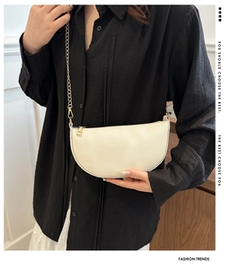 Detailed close-up of white half-moon crossbody bag with golden chain and lychee texture
