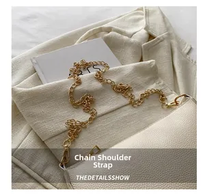 Detail der cremeweißen Lederhandtasche mit Lychee-Muster und goldener Kette auf Anzug