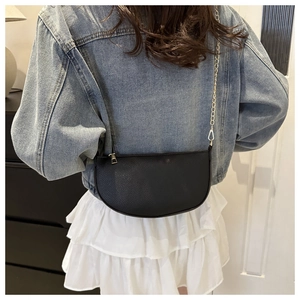 Detail of black crescent crossbody bag with lychee texture and gold chain strap