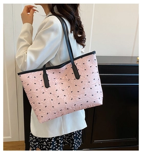 Detail of pink quilted tote bag with black bow patterns and contrast shoulder straps