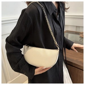 Detailansicht der cremeweißen Baguette-Tasche aus Leder mit goldener Kette