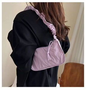 Detail view of light purple nylon underarm bag with pleated ruffle strap on model shoulder