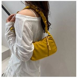 Detail of ginger yellow nylon handbag featuring ruffled shoulder strap and drawstring accents