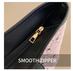 Detail shot of smooth black zipper with gold metal hardware on pink textured tote bag