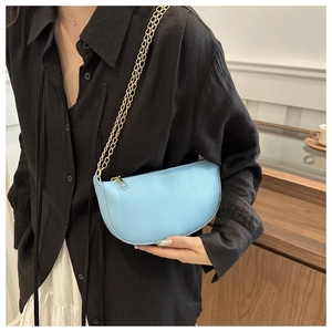 Detail of light blue crescent bag with lychee texture and gold chain strap