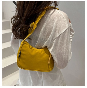 Detail of mustard yellow shoulder bag featuring a knotted strap and FANYISSA brand label