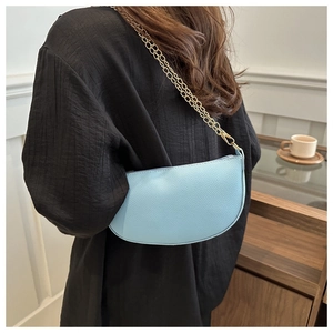 Detail of light blue lychee pattern saddle bag with a delicate gold chain shoulder strap