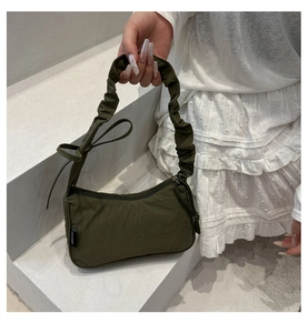 Close-up of olive green pleated nylon handbag showing smooth zipper and brand label