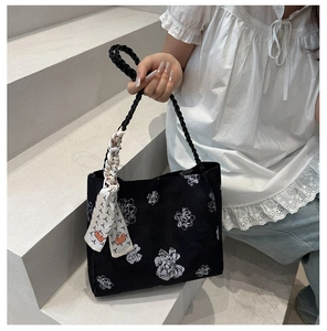 Détail de la broderie florale sur un sac cabas en toile noire avec foulard en soie