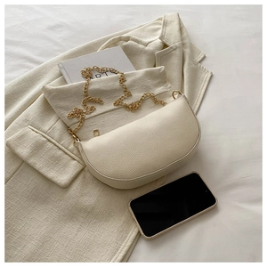 Detail of lychee textured leather crescent bag with elegant gold chain and zipper