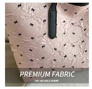 Macro detail of pink tote bag fabric with black bow patterns and leather handle stitching