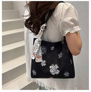 Détail d'un sac seau floral noir avec foulard en soie porté par un mannequin