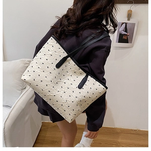 Detail of cream tote bag with black bow patterns and textured bubble fabric finish