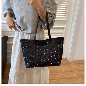 Détail d'un sac cabas noir avec motifs de nœuds blancs et texture en nylon durable