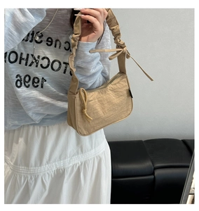 Detail of khaki nylon bag featuring pleated handle and decorative side ribbon bow