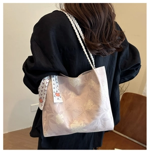 Détail du cabas floral avec anse en corde tressée blanche et foulard porté par un modèle
