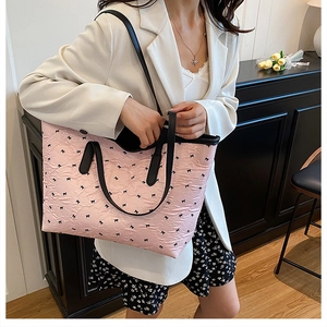 Sac fourre-tout rose avec motifs nœuds noirs porté par un mannequin en tenue d'été chic