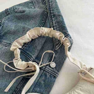Top-down view of a creamy white pleated shoulder bag with a stylish bow on denim