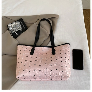 Détail du cabas plissé rose avec imprimés nœuds noirs et doubles bandoulières robustes
