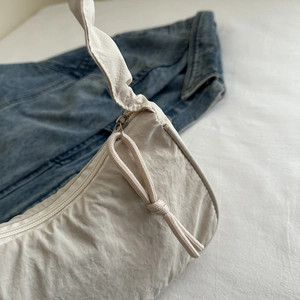 Detail of off-white nylon half-moon bag with pleated texture and zipper detail