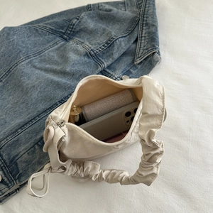 Detail of off-white pleated tote bag showing interior capacity for phone and cosmetics