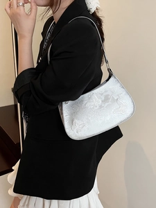 Sac à épaule argenté avec broderie papillon porté par un mannequin avec style