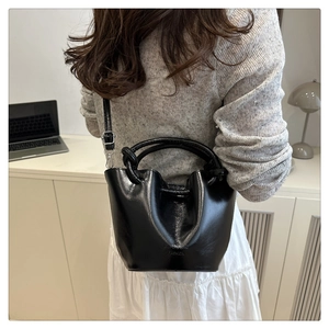 Macro view of black pleated bucket bag detail with adjustable strap and knot handle