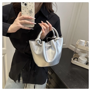 Detail of silver metallic pleated bucket bag with a thick knot handle and logo print