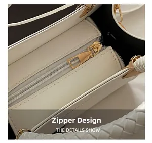 Nahaufnahme des goldenen Reißverschlusses und des gewebten Griffs der weißen Handtasche