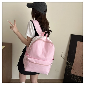Close-up of pink canvas backpack with white lettering and side mesh water bottle pocket