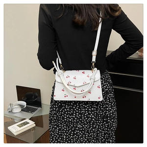 Détail d'un sac bandoulière en cuir PU blanc avec imprimés cerises et poignée à nœud chic