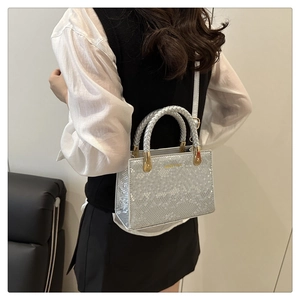Detail der silbernen Schlangenmuster-Handtasche mit Metalltextur und goldenen Griffen