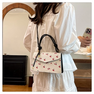 Detail of cherry pattern handbag with black contrast handle and knot detail