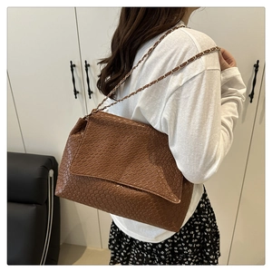 Detail of dark brown woven texture shoulder bag with leather-interwoven chain strap