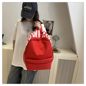 Close-up of red canvas backpack featuring white WIZ lettering and side mesh water bottle pocket