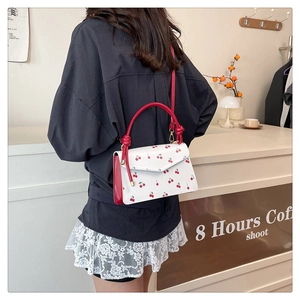 Lifestyle shot of a woman wearing a sweet cherry print crossbody bag in a cozy cafe setting
