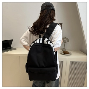 Rear view of black nylon backpack with white artistic letters on minimalist background