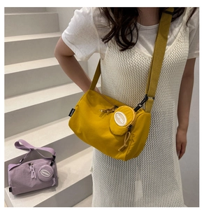 Detailansicht der großen Nylon-Tasche mit passender runder Geldbörse und Markenlabel
