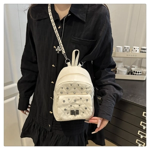 Detail eines weißen gesteppten Mini-Rucksacks mit Silbernieten und Drehverschluss