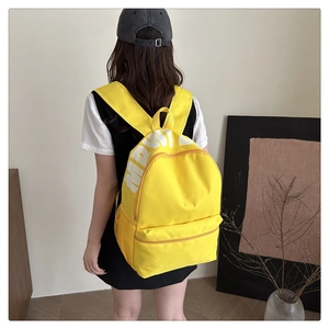 Detail of yellow canvas backpack showing spacious main compartment and side mesh pocket