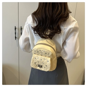 Gesteppter cremefarbener Mini-Rucksack mit silbernen Strass-Details getragen von einem Model