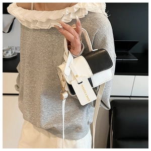 Detail of black and white patchwork mini crossbody bag with gold text brand tag