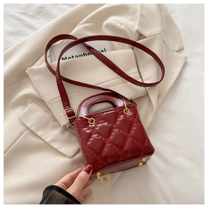Detail of burgundy quilted leather square bag with gold studs and adjustable strap